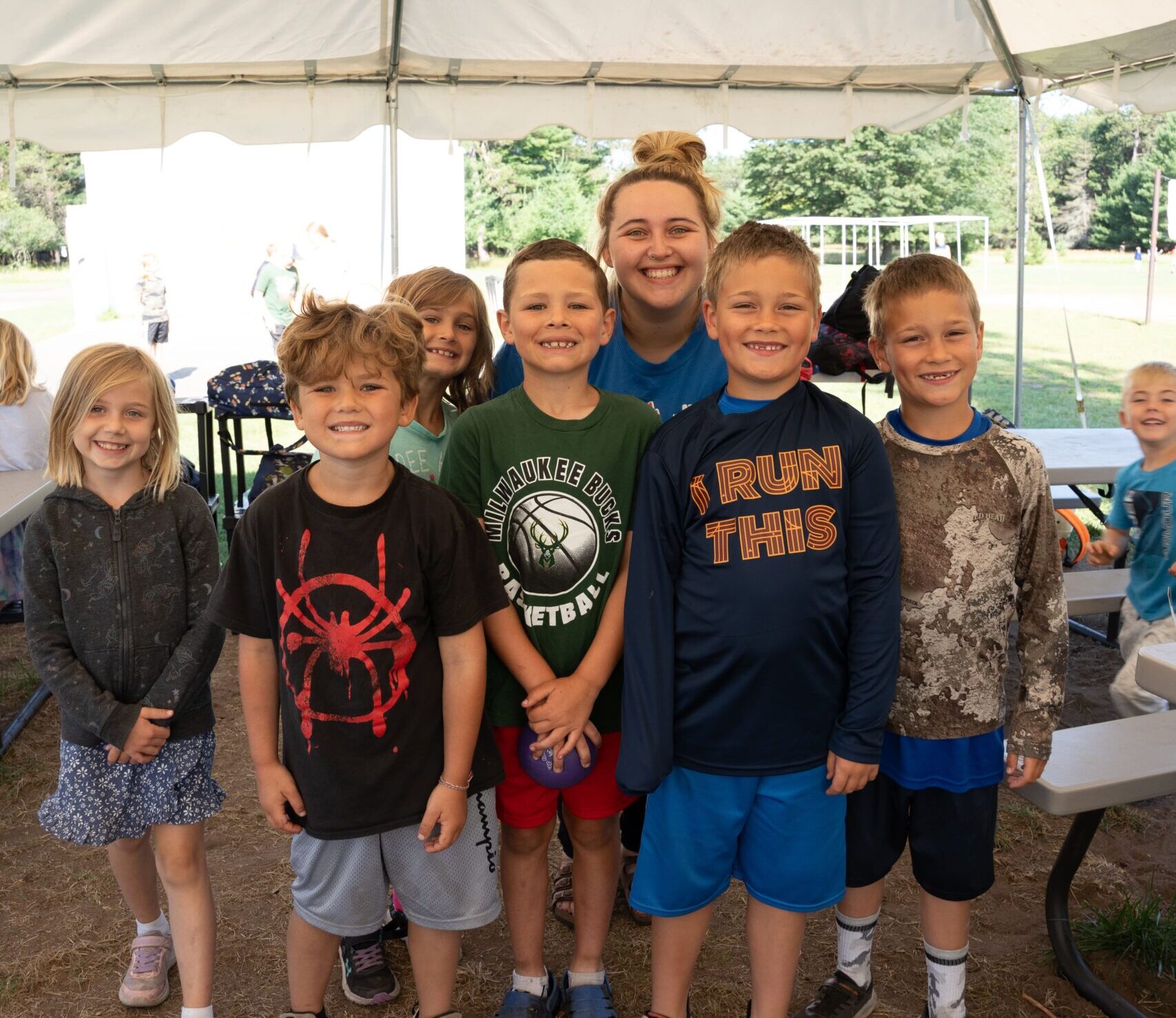 Group-of-kids-with-staff-smiling-under-tent-min